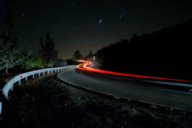 The back light of a car is making a line on a mountain road